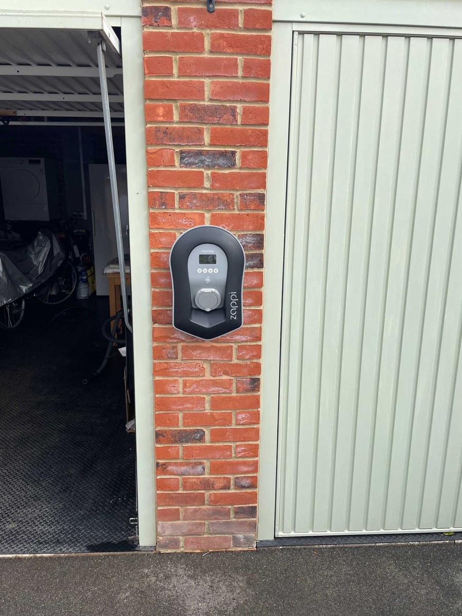 EV charger fitted on a brick pillar by a garage